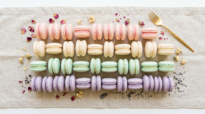 Overhead flat-lay of pastel macarons in a color gradient on linen for weddings.